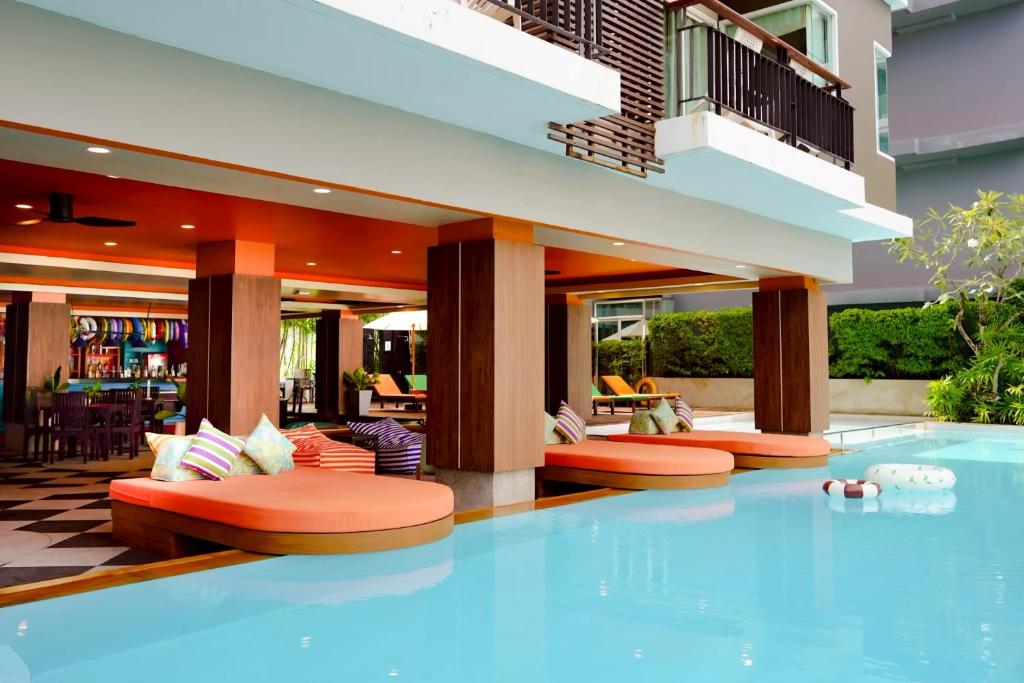 Ein Hotelpool mit orangefarbenen Kissen auf dem Boden in der Unterkunft Andakira Hotel - SHA Extra Plus in Patong Beach
