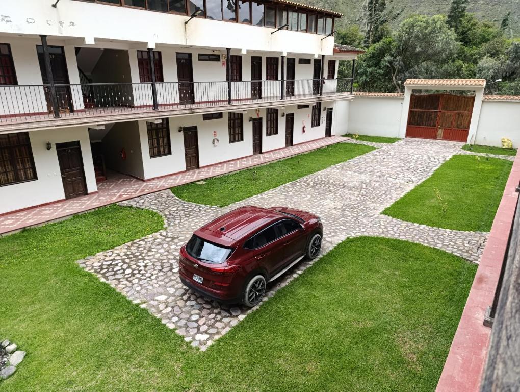 ein rotes Auto, das vor einem Gebäude geparkt ist in der Unterkunft Samana House Ollantaytambo in Ollantaytambo