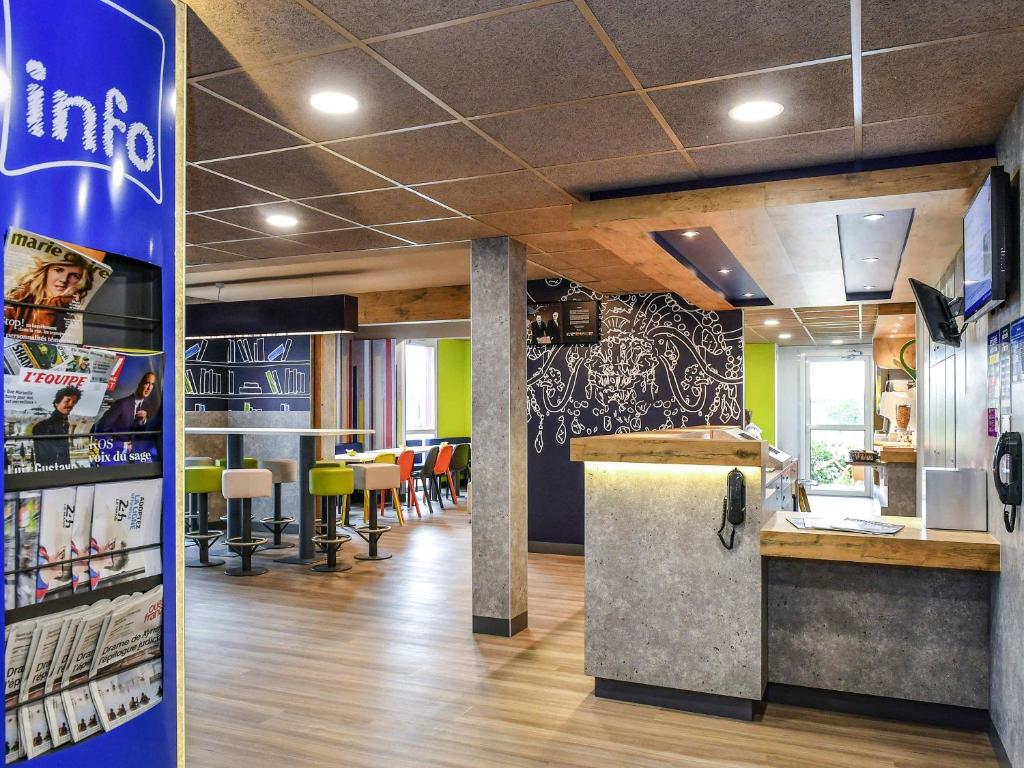 a restaurant with a counter and a bar with chairs at ibis budget Coutances in Coutances