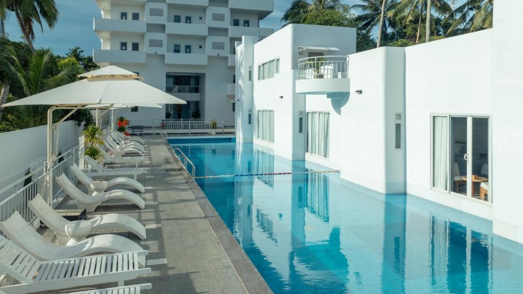uma piscina com cadeiras e um guarda-sol ao lado de um edifício em The Up Hotel Phu Quoc Island - The Poolside Escape em Duong Dong