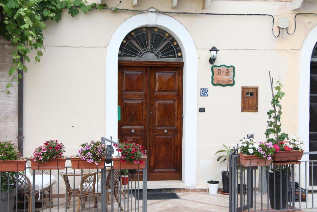 une porte menant à un bâtiment avec des tables, des chaises et des fleurs dans l'établissement L'incanto del mare, à Acciaroli