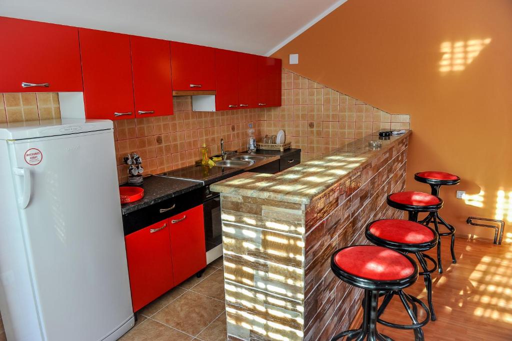 uma cozinha com armários vermelhos e bancos vermelhos em Apartman Selena em Trebinje