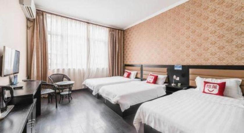 a hotel room with two beds and a desk and a television at PAI Hotel Beijing Capital International Airport Linhe Development Zone in Tahe