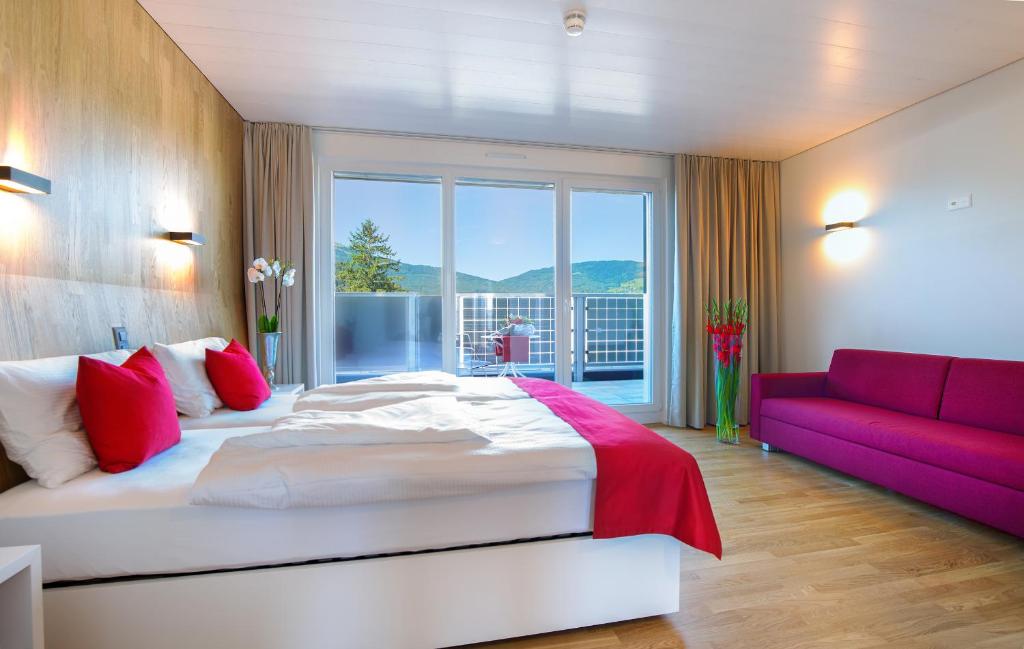 a bedroom with a large bed and a red couch at Hotel Restaurant Rhy in Oberriet