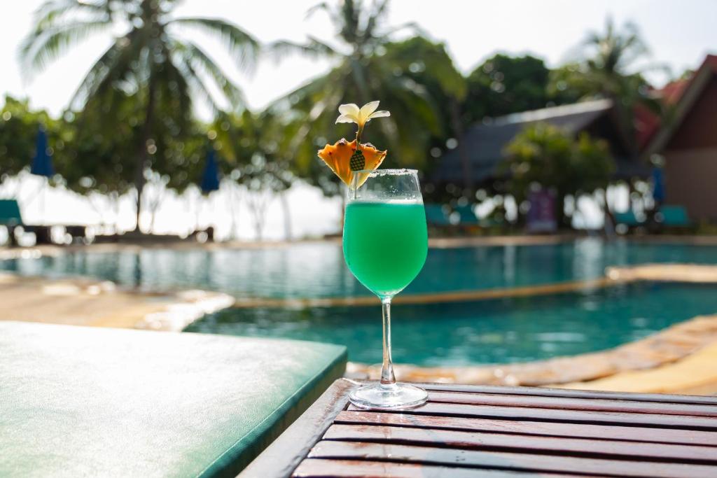 a drink sitting on a table next to a swimming pool at Dream Team Beach Resort in Ko Lanta