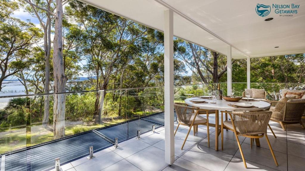 Una habitación con balcón con mesa y sillas. en Tree Tops Water Front Soldiers Point- First Floor, en Soldiers Point