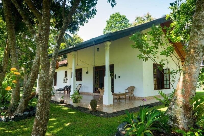 una casa blanca con árboles en el patio en Hikkaduwa magnoon villa, en Hikkaduwa