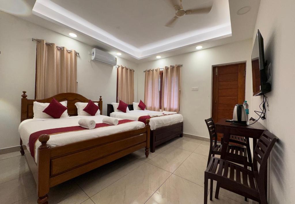 a bedroom with two beds and a desk and a television at Kaarthik Residency in Pondicherry