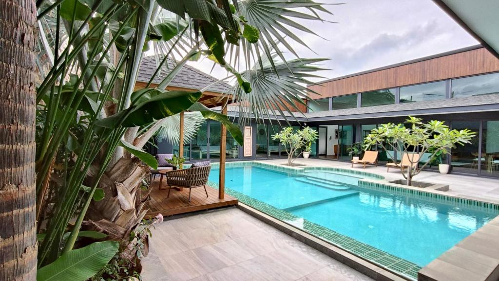a swimming pool in a house with a palm tree at Sarang Jati Mansion in Ban Saiyuan (1)