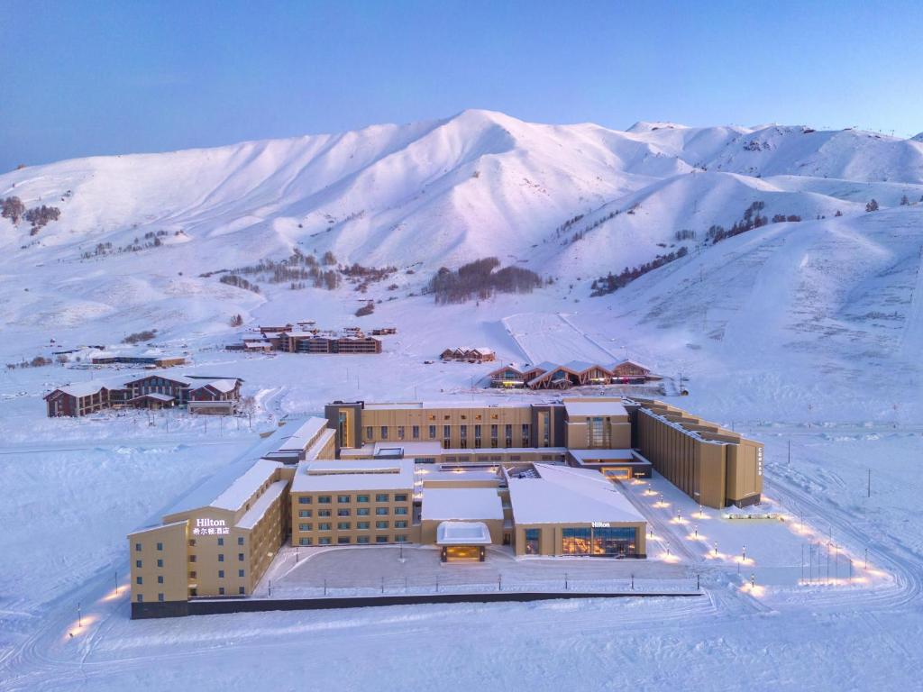 a building on top of a snow covered mountain at Hilton Altay Hemu in K'u-mu