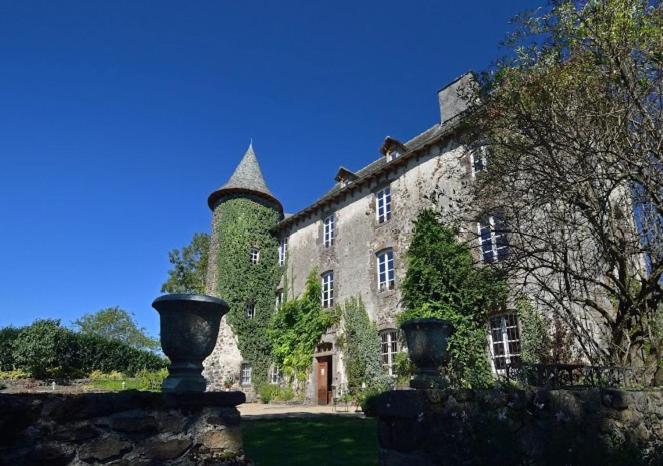 un grand bâtiment en pierre avec une tour en haut dans l'établissement Château de Taussac, à Taussac