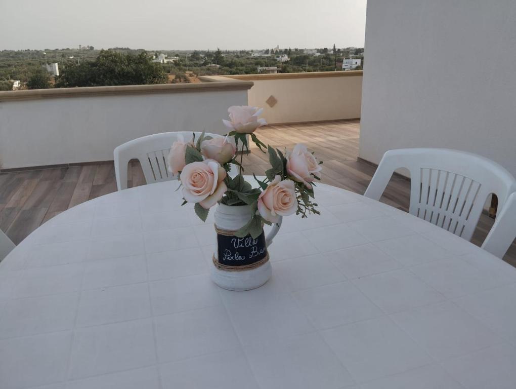 een vaas gevuld met roze rozen zittend op een tafel bij Villa Perla Bianca-Privacy e relax vicino Polignano in Polignano a Mare