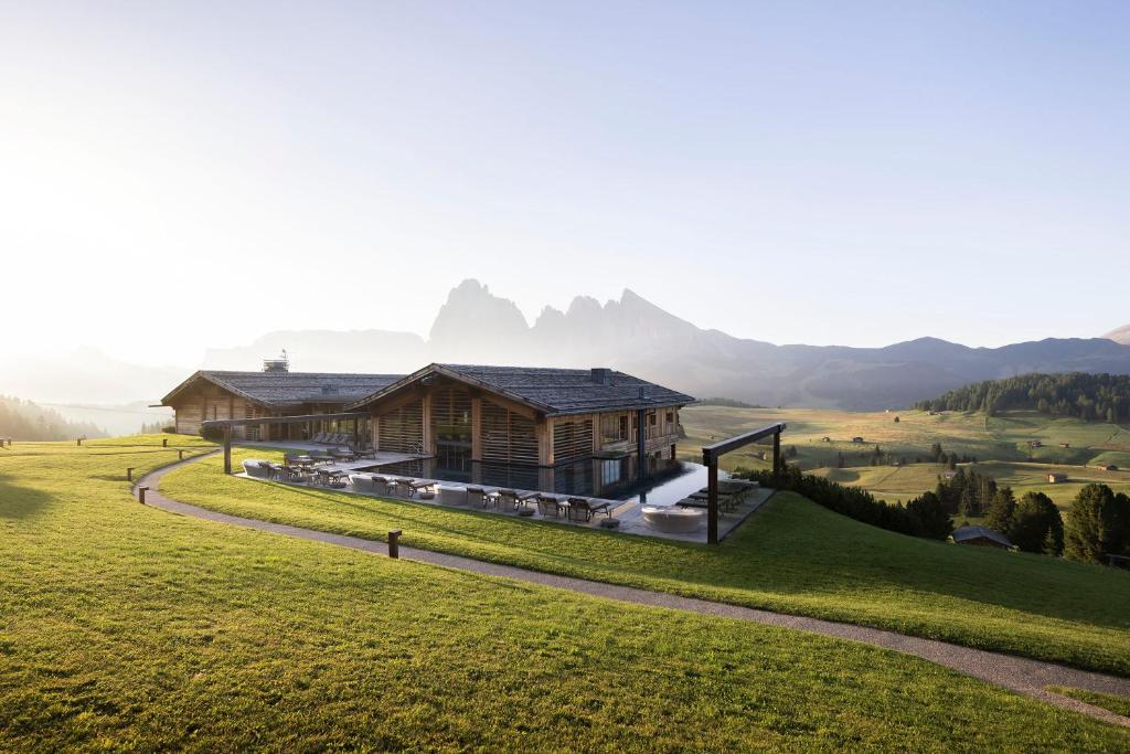 a house on a hill with mountains in the background at ADLER Alpe in Alpe di Siusi