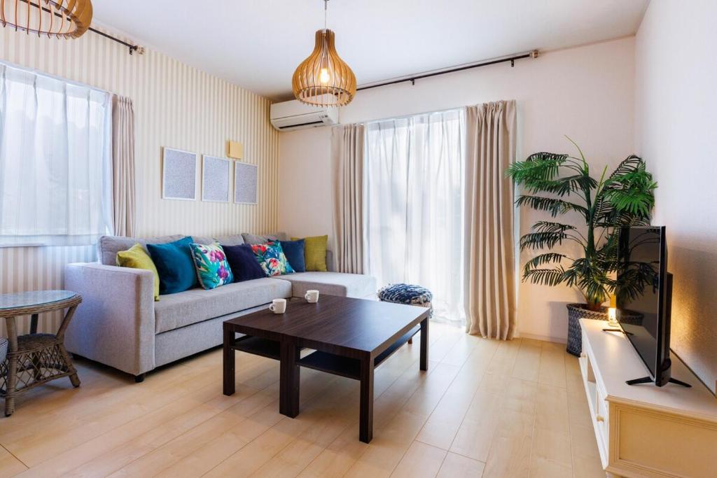 a living room with a couch and a table at 本部町 最大12名宿泊可 無料駐車場2台付き 家族 グループに最適 Terrace Motobu in Motobu