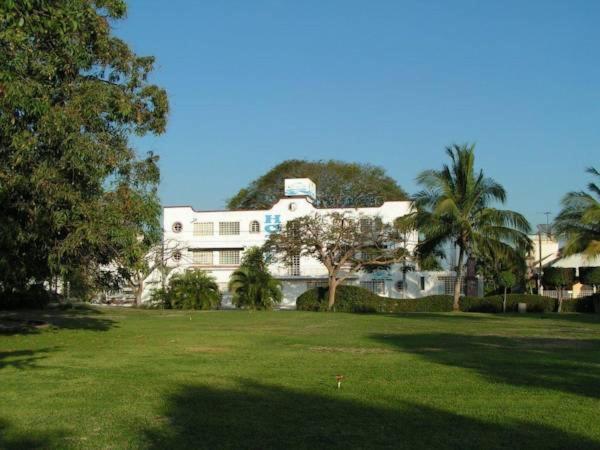 a large white house with palm trees in a field at Hotel Olinalá Diamante in Acapulco