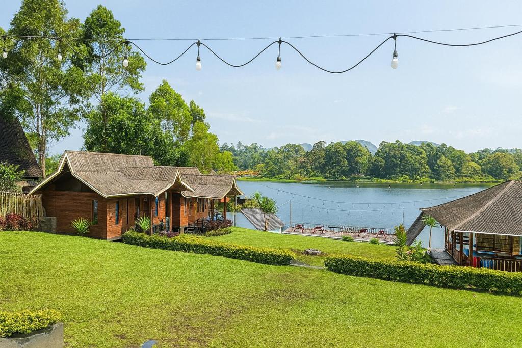 a house with a lawn and a lake at Villa TB Pangalengan Bandung RedPartner in Palayangan