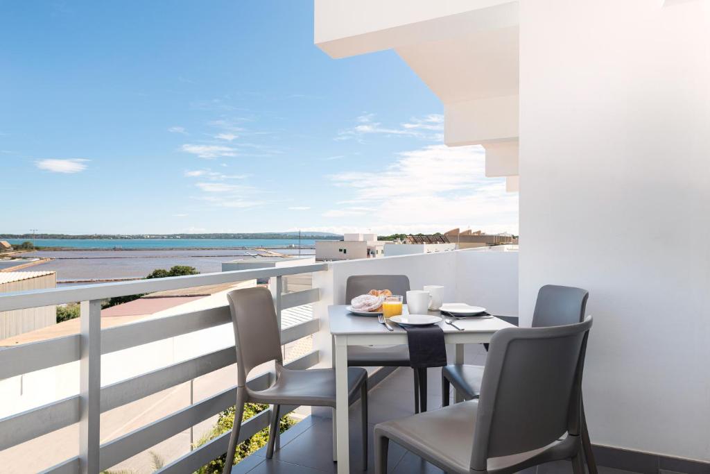a balcony with a table and chairs and a view of the ocean at Apartaments S'Estanyol in La Savina