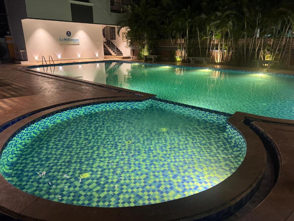 een groot zwembad met blauwe lichten in een gebouw bij La Millionaire Resort in Auroville