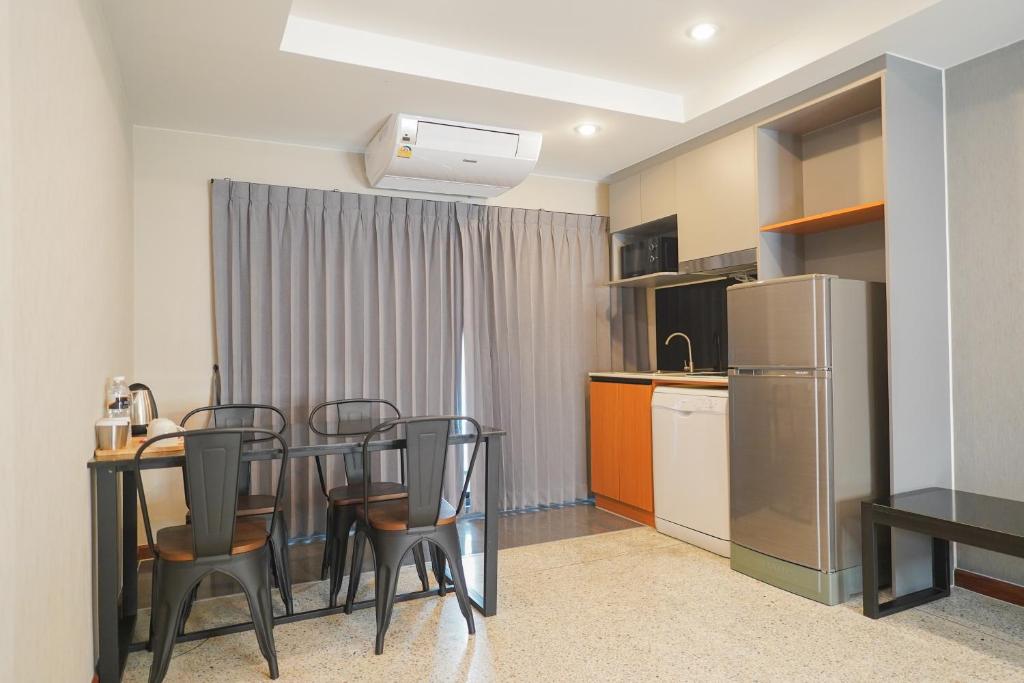 A kitchenette and dining corner with four chairs, a refrigerator, and a curtained window or door.