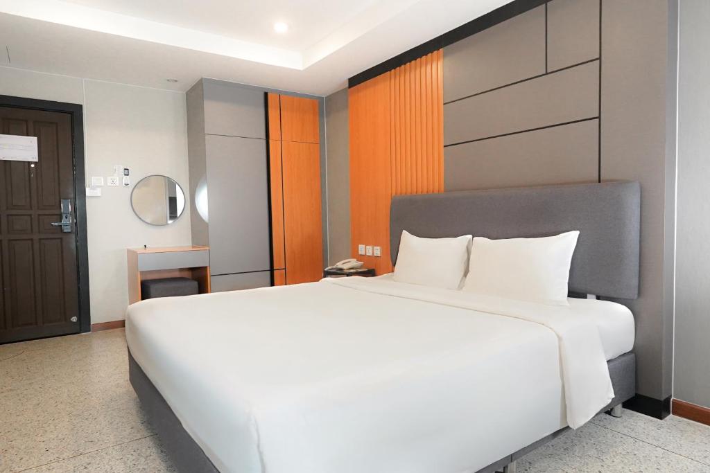 A large bed in a modern room with a dressing table, wardrobe, and entry door.
