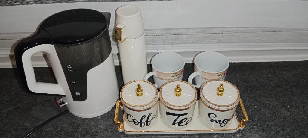 uma cafeteira e quatro xícaras em uma bandeja em Nastaran Nest em Oberhausen