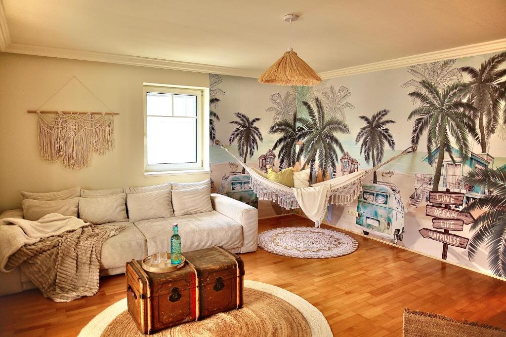 a living room with a couch and palm trees mural at Ganswoanders - deine kleine Beach Oase am Traunsee in Gmunden