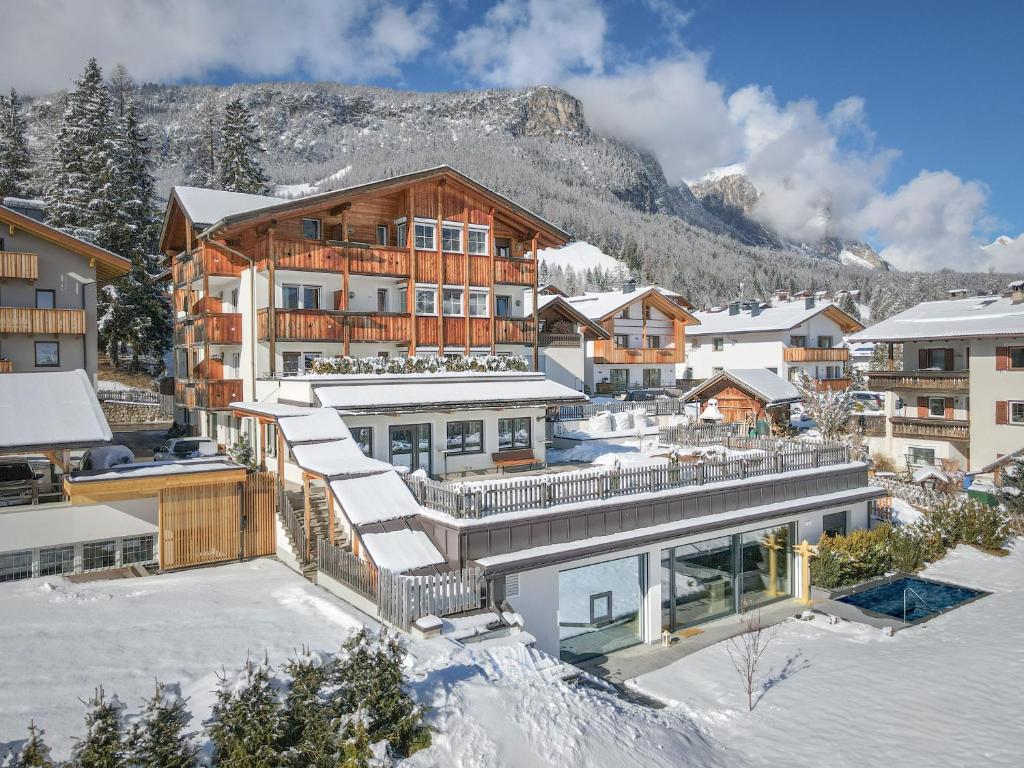 um edifício na neve com uma montanha ao fundo em Pensione Camoscio em La Villa