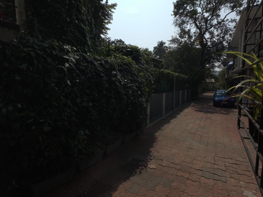un marciapiede di mattoni accanto a una recinzione con un'auto sopra di Luxury 1BHK Cozy Ambience Pool Full Kitchen ad Assagao