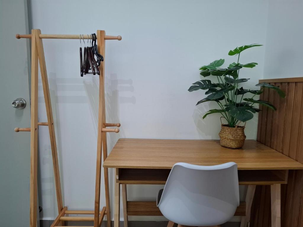 a wooden table with a white chair and a plant at Amber Cove - Luxury Design By Luxpro Management - 6~7 pax in Melaka