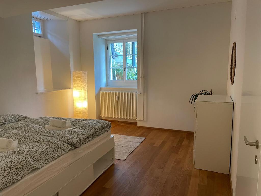 una camera da letto bianca con un letto e una finestra di Spacious light-flooded apartment with garden at Lake Zurich a Männedorf