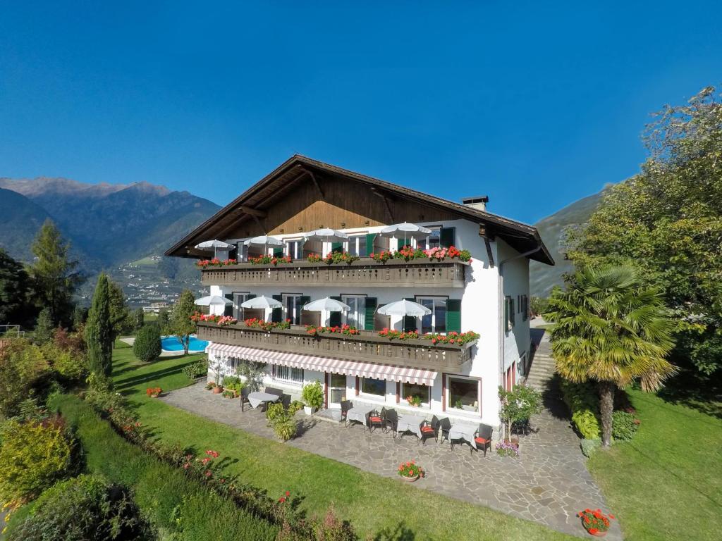 een groot wit gebouw met een balkon met bloemen bij Garni Pluner in Schenna