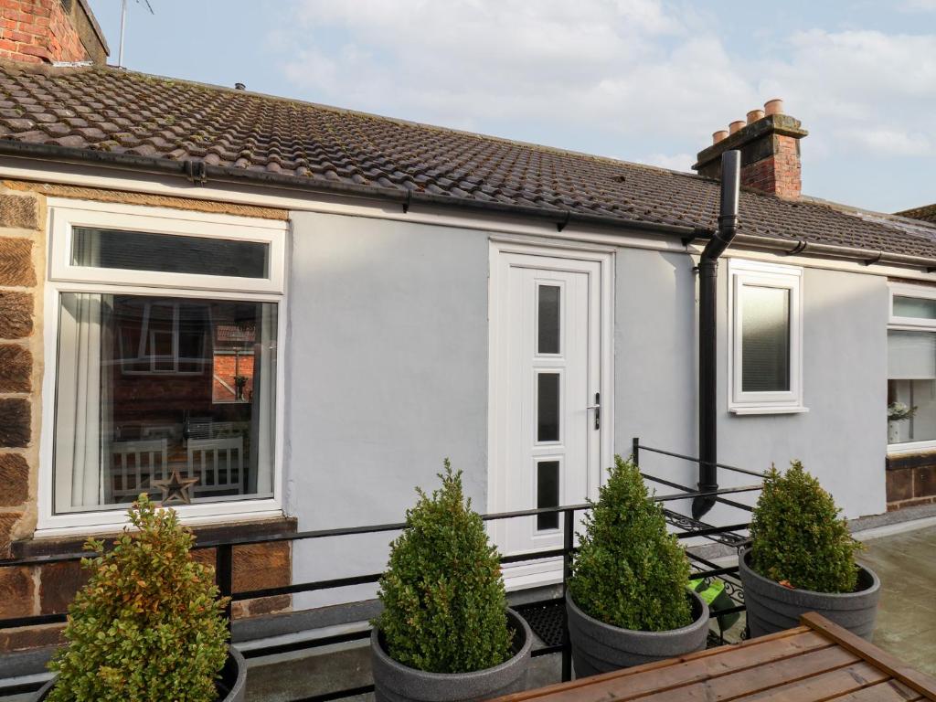 a white house with potted trees in front of it at Postmans Lodge in Middlesbrough