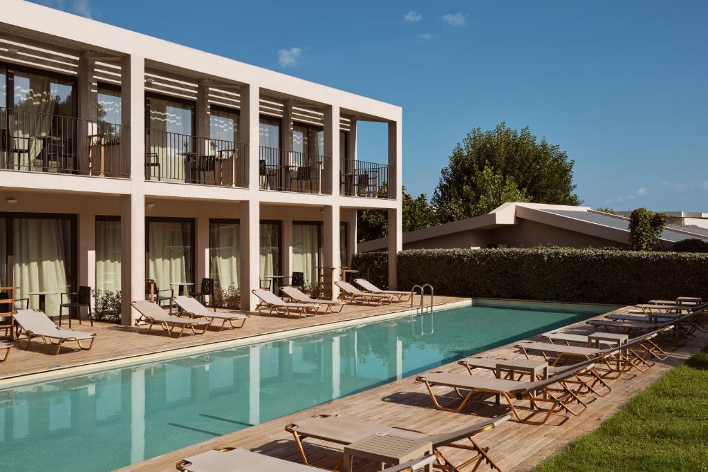 a hotel with a swimming pool and lounge chairs at New Beach Hotel in Planos