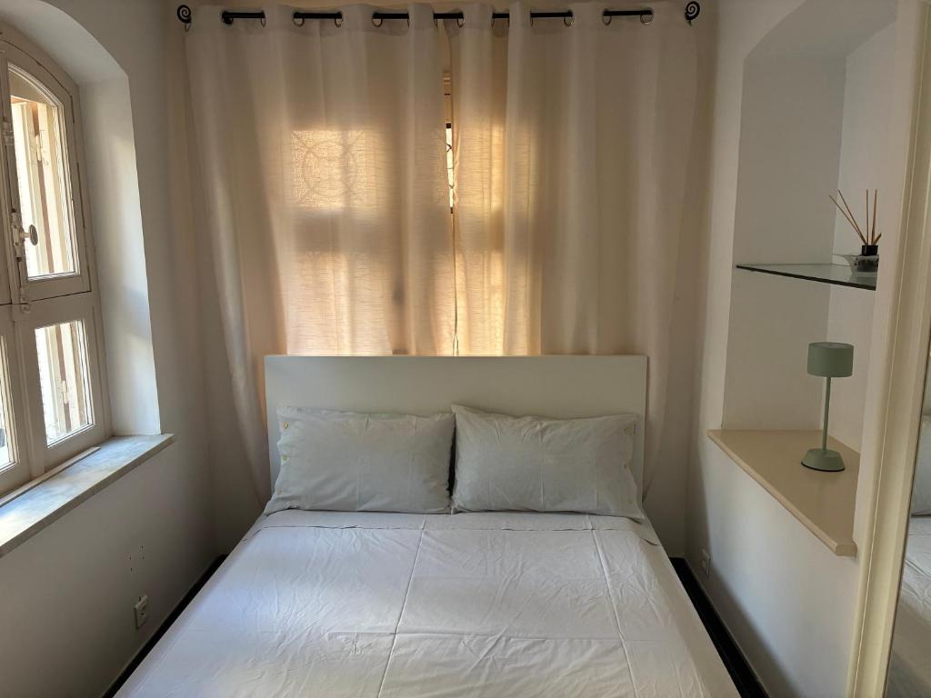 un letto bianco in una stanza con una finestra di Appartement Louis a Cap d'Ail