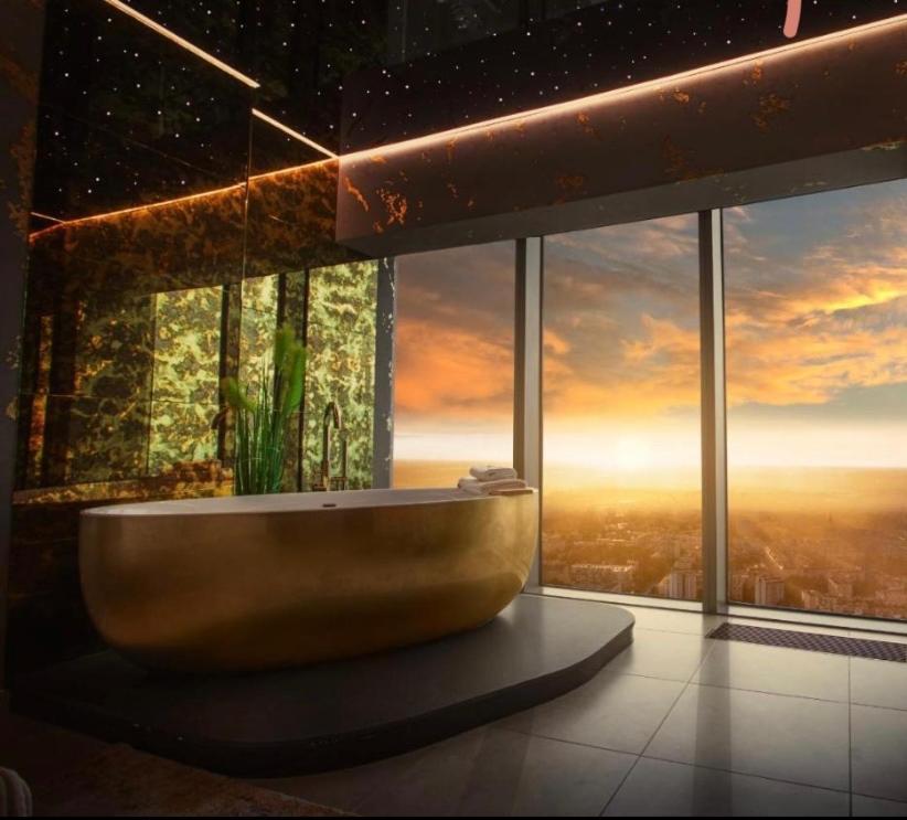 łazienka z wanną przed dużym oknem w obiekcie Hanza Tower SKY GOLD 24 Sauna & Jacuzzi & Pool & SPA w Szczecinie