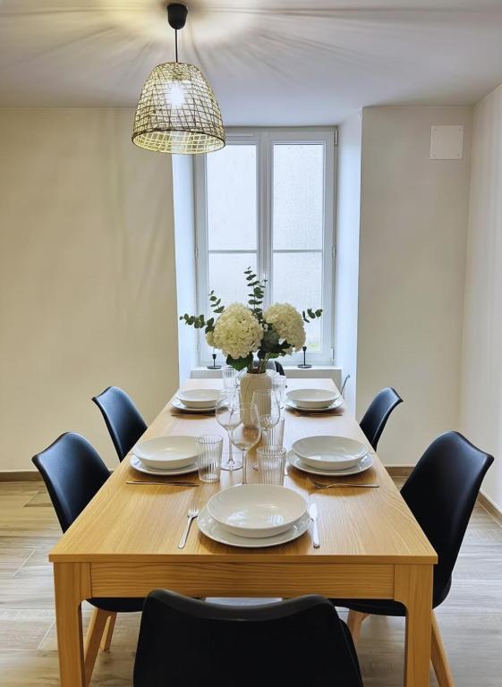 a dining room table with chairs and a vase of flowers at Logis du Mousquetaire -15min du Parc - by R&G in La Pommeraie-sur-Sèvre