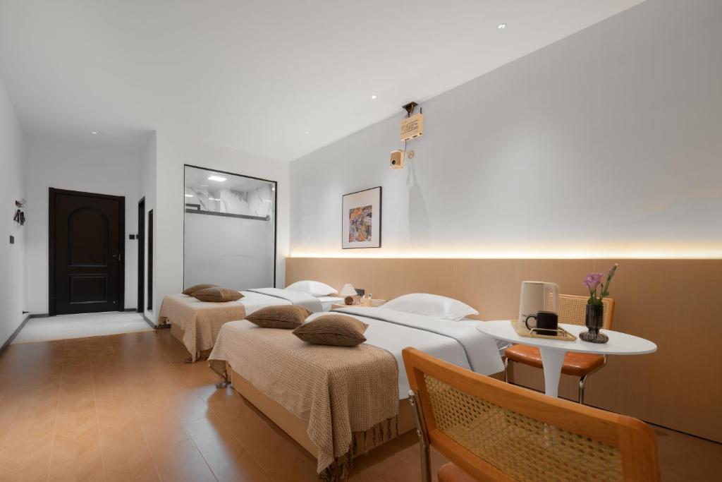 a room with three beds and a table and a table at Summer & Chihiro Hotel in Xiamen