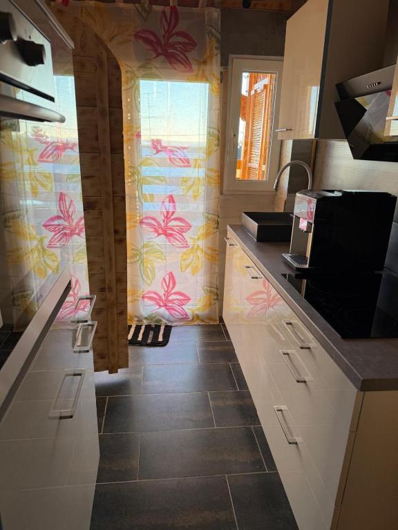 una cucina con armadi bianchi e fiori rosa sul muro di Moderne 1-Zimmer-Ferienwohnung a Niederdorla