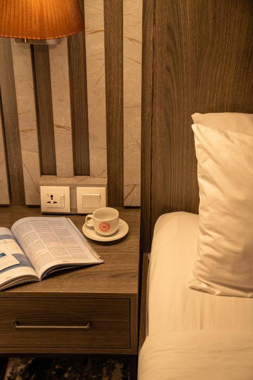 代胡克Wan Hotel的一张床，床上有一张桌子，桌子上放着一本书和一杯咖啡。