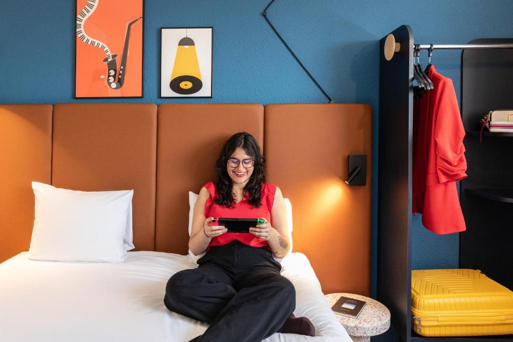 uma mulher sentada na cama segurando um tablet em ibis Paris Porte de Montreuil em Paris