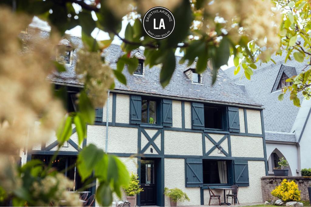 a white building with black windows and a sign that reads la at La Sainthilarienne in Saint-Lary-Soulan
