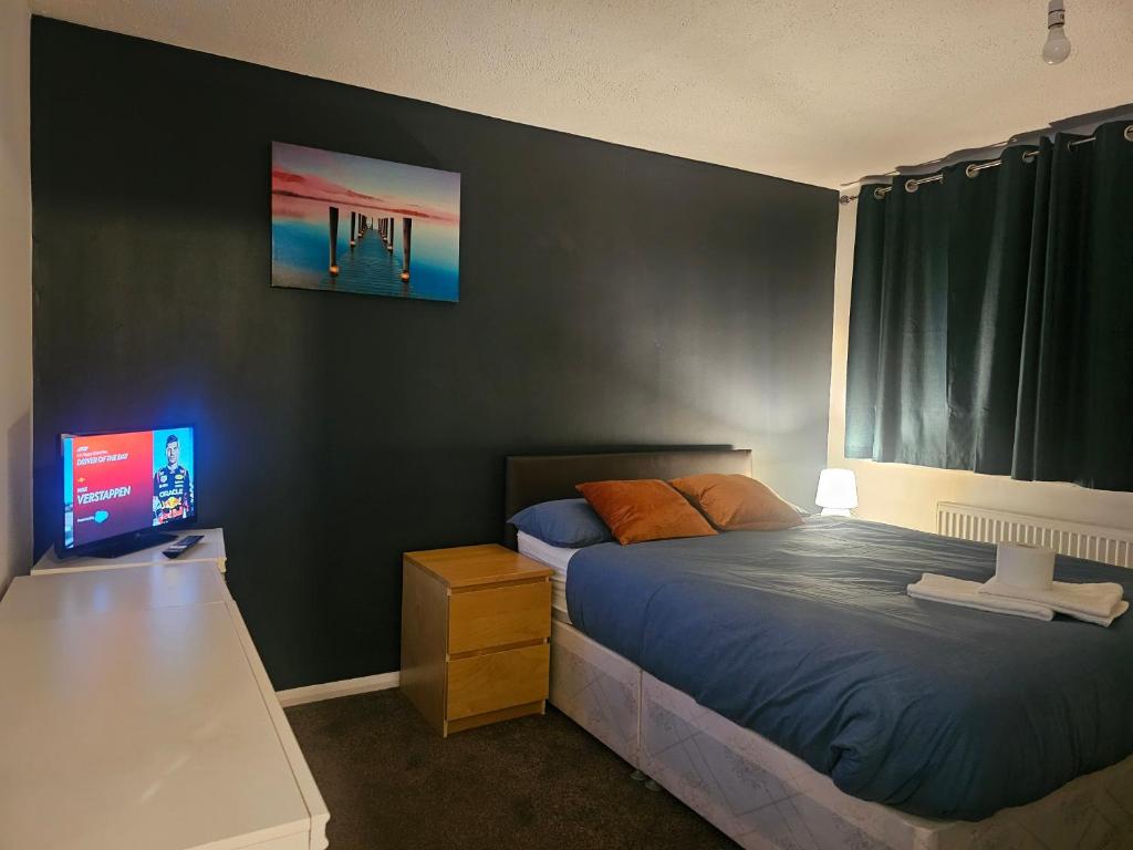 a bedroom with a bed and a flat screen tv at Rosag Guest House Rainham in Rainham