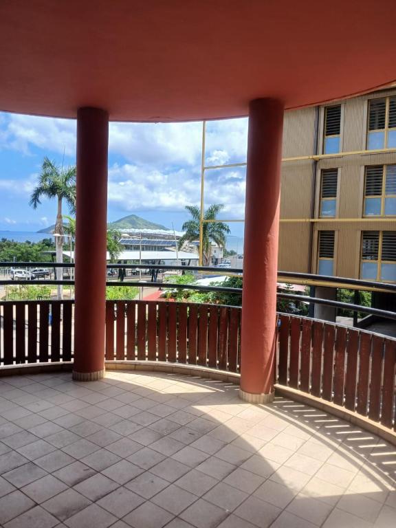 einen Balkon mit Blick auf ein Gebäude mit Palmen in der Unterkunft Dago-Nid Baobab Appartement in Mamoudzou