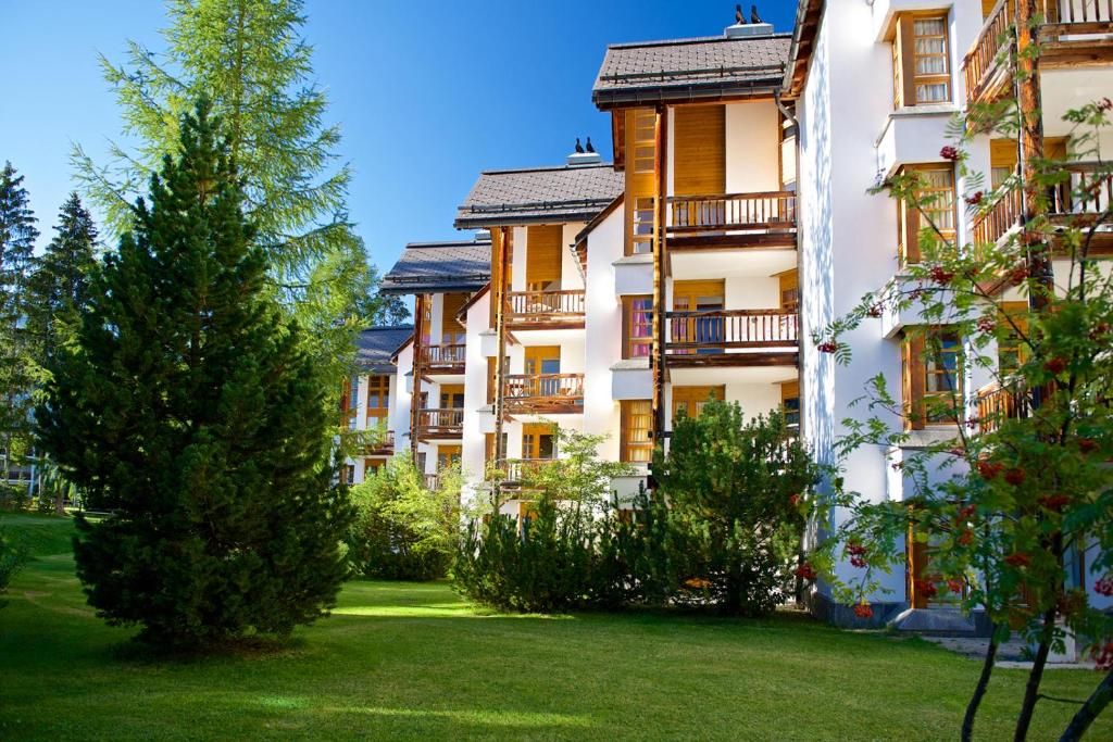 an apartment building with trees in the yard at Schweizerhof Ferienwohnungen Lenzerheide Haus 5 in Lenzerheide