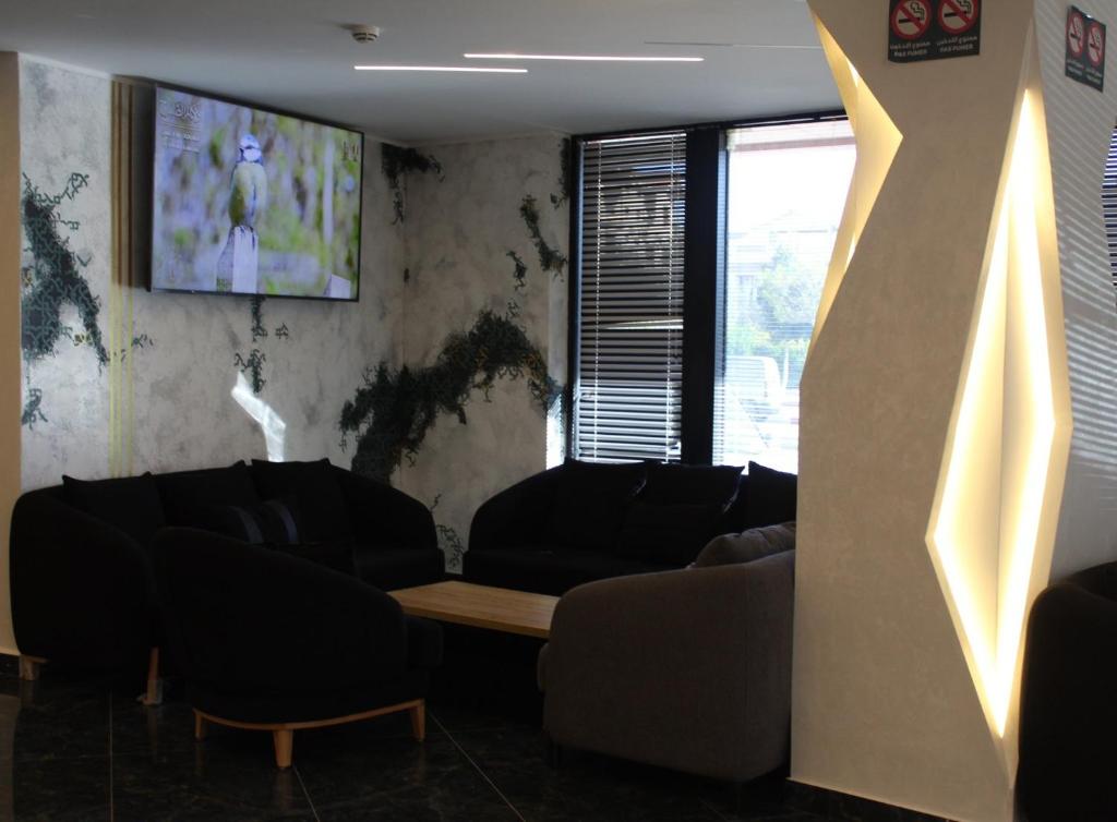 a living room with couches and a tv on the wall at El Fares Hôtel Spa & Conférences in Bordj Bou Arreridj