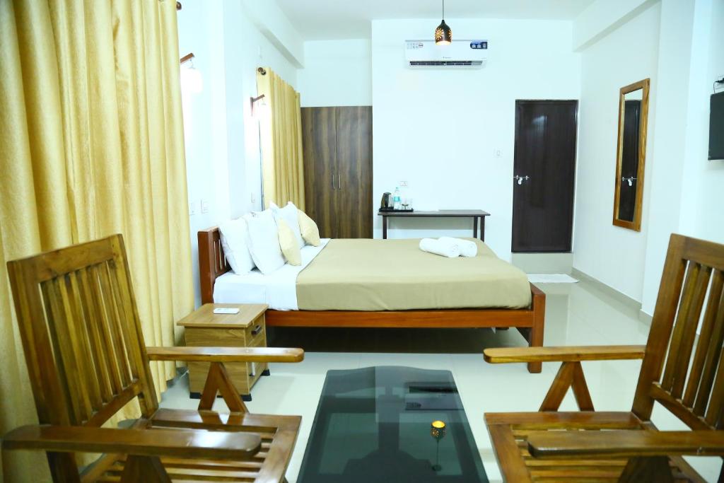 Una habitación de hotel con una cama y dos sillas. en Oxxon Airport Hotel, en Angamaly