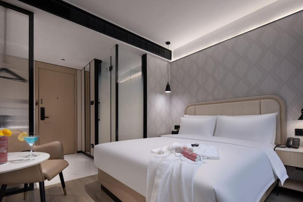 Huanman Hotel Changsha Yuelushan Yingwan Town Metro Station Branch في تشانغشا: غرفة نوم بها سرير أبيض كبير وطاولة