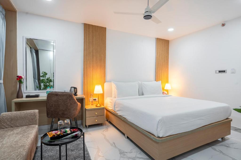 a bedroom with a bed and a desk and a chair at Rcc Hotels Gachibowli in Hyderabad