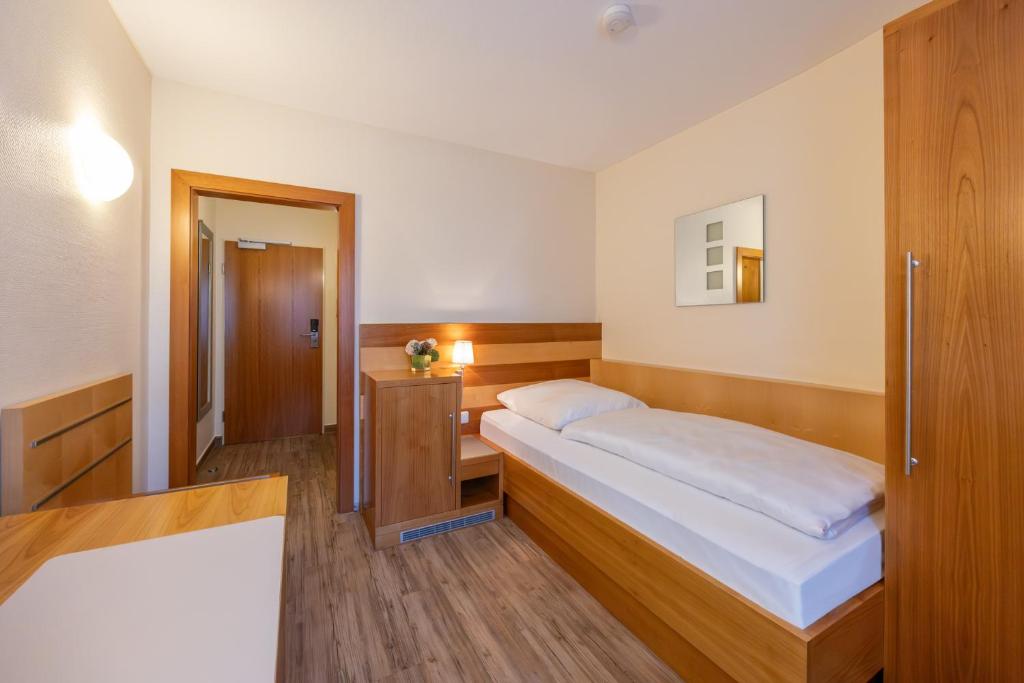 a bedroom with a bed and a wooden cabinet at Hotel Carlton in Duisburg