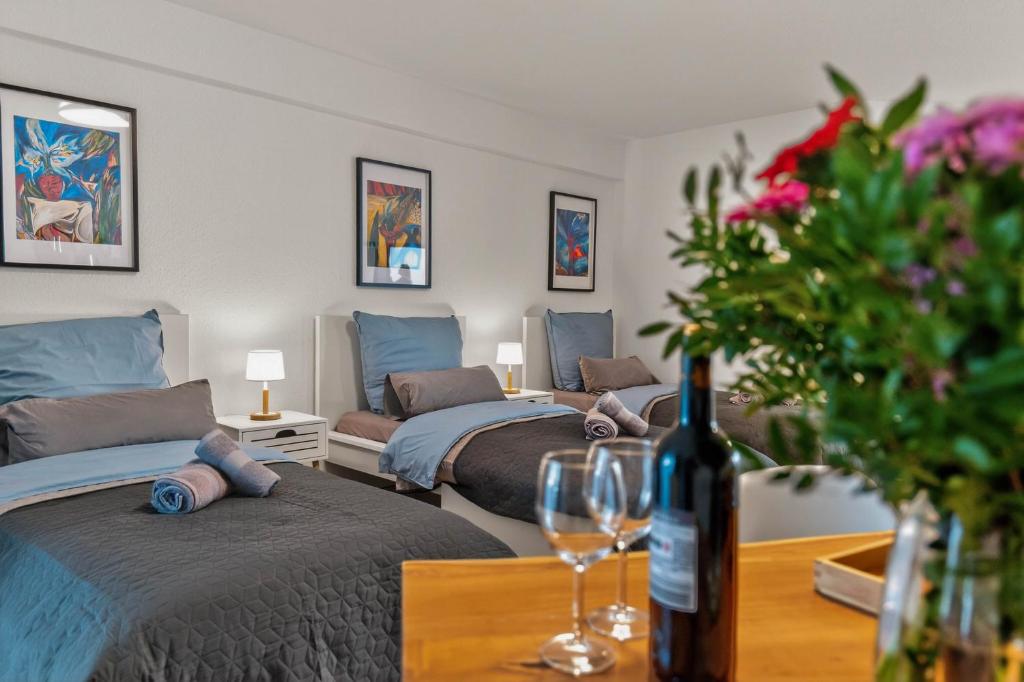 布雷滕Lara - Stilvolle 3-Zimmer-Unterkunft im Herzen von Bretten的客房设有三张床和一张带一瓶葡萄酒的桌子。